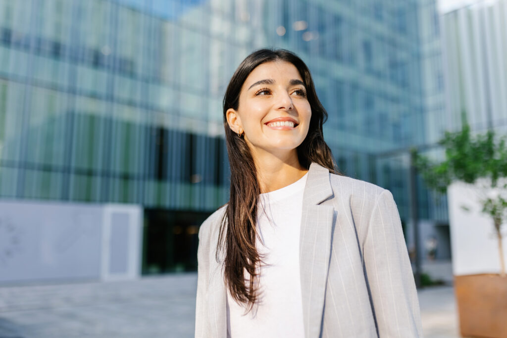 A young, confident business professional standing outside an office building.